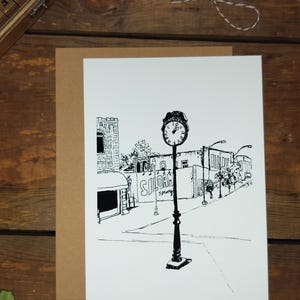 May include: Black and white illustration of a street scene with a clock tower, buildings, and streetlights. The clock tower has a clock face with Roman numerals and the text "Siloam Springs" is visible on a building.