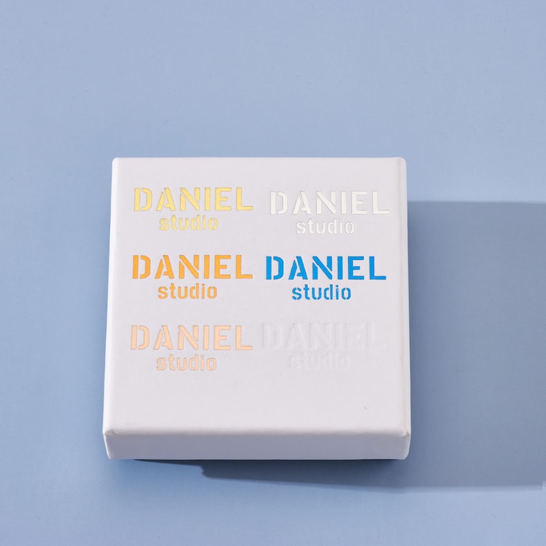 May include: White box with the text "DANIEL studio" repeated four times in different colors, including orange, yellow, blue, and white.
