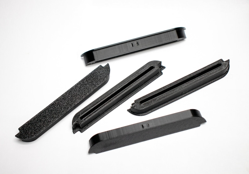 May include: Five black plastic pieces with a variety of shapes and sizes. Some pieces have a groove running down the center.