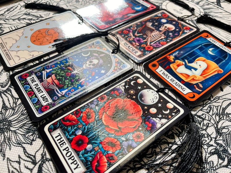 May include: A set of ten tarot cards with black tassels. The cards feature colorful illustrations with titles such as "The Plant Lady", "The Poppy", "I Was Reading", "Wheel of Fortune", and "Sorry I Ghosted".