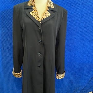 May include: A black blazer with a leopard print collar and cuffs. The blazer has a button-up front and long sleeves.