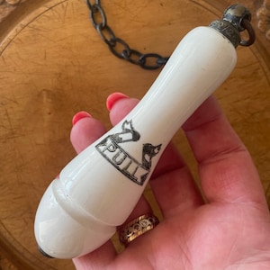 May include: White porcelain toilet chain pull with a black 'PULL' inscription on a banner. The pull has a metal loop at the top.