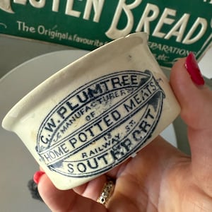 Peut inclure: Un pot en céramique blanche avec une inscription bleue qui dit "C.W. PLUMTREE MANUFACTURER OF HOME POTTED MEATS 13 RAILWAY ST. SOUTHPORT"