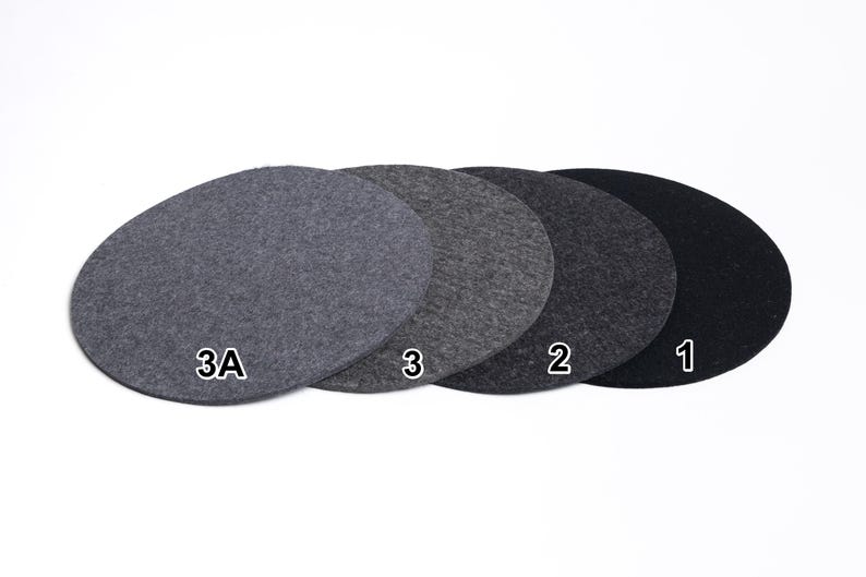 Puede incluir: Cuatro posavasos circulares de fieltro dispuestos en fila, mostrando un degradado de tonos grises de claro a oscuro. Cada posavasos est&aacute; etiquetado con texto blanco: 3A para el gris claro, 3 para el gris medio, 2 para el gris oscuro y 1 para el negro.
