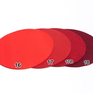 Puede incluir: Cuatro posavasos circulares de fieltro dispuestos en fila, que muestran un degradado de tonos rojos desde el escarlata brillante hasta el burdeos intenso. Cada posavasos est&aacute; etiquetado con un n&uacute;mero blanco: 16, 17, 17B y 18.