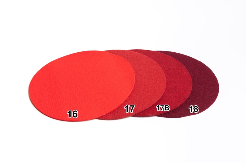 Puede incluir: Cuatro posavasos circulares de fieltro dispuestos en fila, que muestran un degradado de tonos rojos desde el escarlata brillante hasta el burdeos intenso. Cada posavasos est&aacute; etiquetado con un n&uacute;mero blanco: 16, 17, 17B y 18.