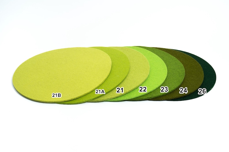 Puede incluir: Una colecci&oacute;n de siete posavasos circulares de fieltro dispuestos en fila, que muestran un degradado de tonos verdes desde el lima claro hasta el verde bosque profundo. Cada posavasos tiene un texto blanco: 21B, 21A, 21, 22, 23, 24 y 26.