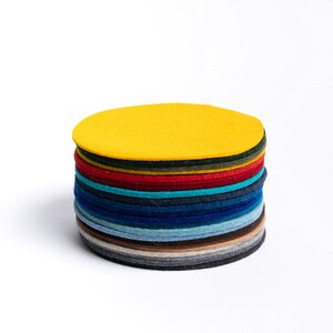 Puede incluir: Una pila de círculos de fieltro de colores, comenzando con un círculo amarillo brillante en la parte superior y pasando a gris oscuro en la parte inferior.