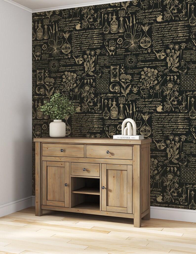 May include: A wooden cabinet with three drawers and two doors. The cabinet is in front of a black and gold wallpaper with a botanical and alchemical design. The wallpaper features illustrations of plants, herbs, and scientific instruments.