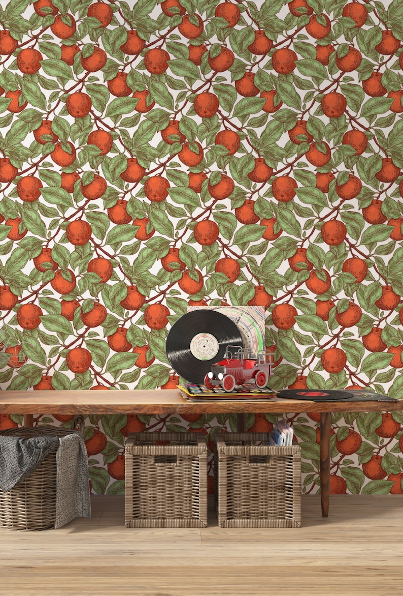 May include: A wooden bench with two wicker storage baskets and a red toy truck on top. The wall behind the bench is covered in wallpaper with a repeating pattern of orange apples and green leaves.