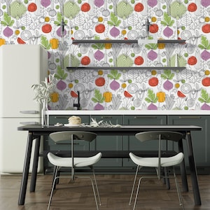 May include: A kitchen with a white refrigerator and green cabinets. The backsplash is a white wallpaper with a colorful vegetable pattern. There is a black table with two black chairs in front of the cabinets.