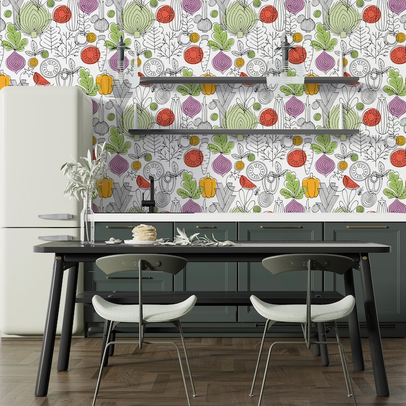 May include: A kitchen with a white refrigerator and green cabinets. The backsplash is a white wallpaper with a colorful vegetable pattern. There is a black table with two black chairs in front of the cabinets.