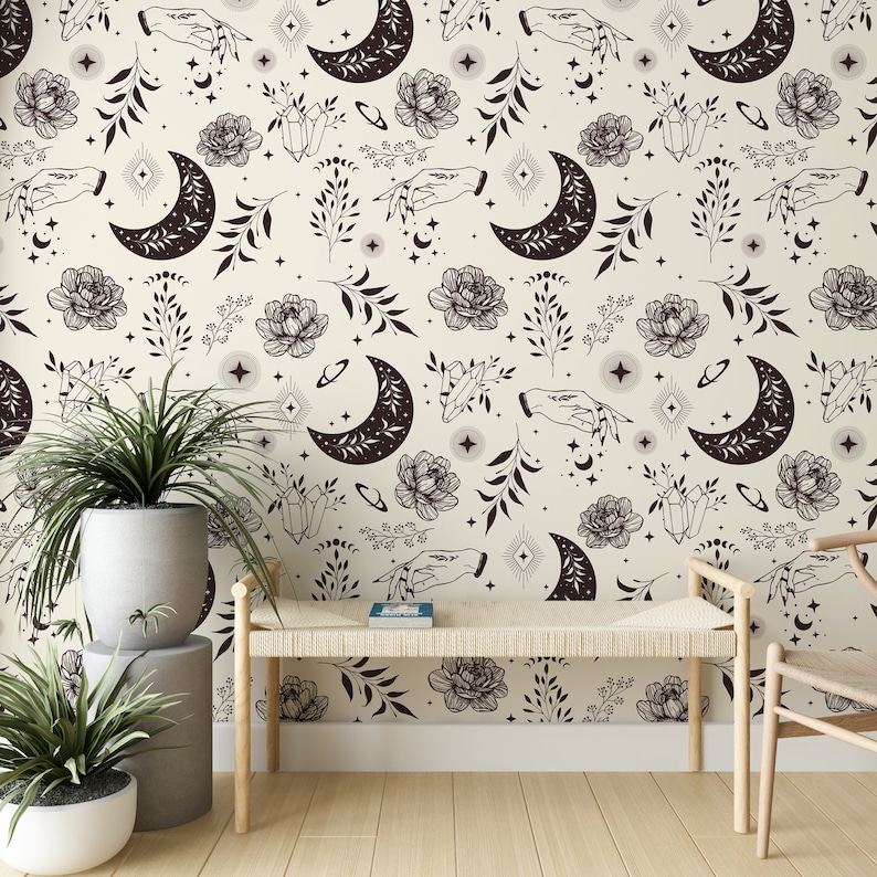 May include: A beige wallpaper with a repeating pattern of black crescent moons, stars, flowers, crystals, and hands. The wallpaper is in a room with a wooden bench and a chair.