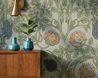 May include: A brass wall sconce mounted on a wall with floral wallpaper featuring green vines, peach flowers, and dark blue accents. A wooden cabinet sits below with a small blue vase and a green plant in a blue pot placed on its surface.