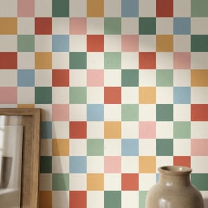 May include: A colorful checkered pattern wallpaper in a grid of squares. The squares are in shades of red, pink, green, blue, and yellow, set against a cream background. A wooden framed picture and a brown vase are in the foreground.
