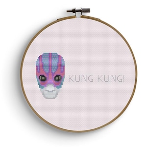 Può includere: Schema di punto croce con un viso alieno rosa, blu e viola con il testo "Kung Kung!" su uno sfondo bianco.