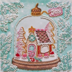 May include: A gingerbread house decorated with pink, white, and gold beads is inside a glass dome with a gold crown on top. The dome is surrounded by white and blue beaded branches.