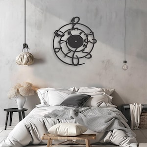 May include: Black metal wall art featuring a treble clef design with a circular shape. The art is displayed on a white wall above a bed with white bedding and a gray throw blanket.