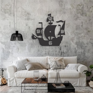 May include: Black metal wall clock shaped like a ship with Roman numeral markings. The clock is mounted on a gray wall in a living room setting with a white couch and a coffee table.
