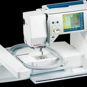 May include: A white and silver Bernina Artista 640 sewing and embroidery machine. It features a color touchscreen, blue accents, and an embroidery hoop. The machine has the brand name and model number printed on the side.