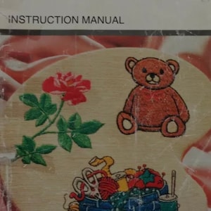 May include: A Singer Quantum XL-100 instruction manual with images of embroidered designs, including a rose, a teddy bear, and a basket of sewing supplies.