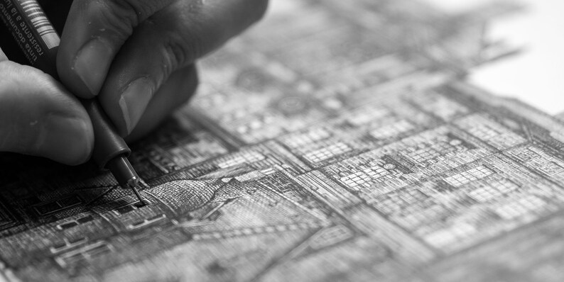 Puede incluir: Imagen en blanco y negro de una mano usando un bol&iacute;grafo de punta fina para dibujar una ilustraci&oacute;n arquitect&oacute;nica detallada. El bol&iacute;grafo est&aacute; en &aacute;ngulo, creando l&iacute;neas y sombreado precisos en el papel. La obra de arte representa una ciudad compleja.
