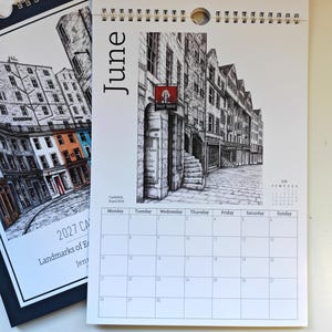 May include: A 2027 wall calendar page for June featuring a black and white ink illustration of Castlehill on the Royal Mile. The page includes a grid for the month, a small July calendar, and a red sign labeled Jolly Judge on a stone building.