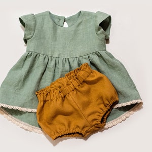 May include: A sage green linen dress with a lace trim and a matching pair of mustard yellow linen bloomers.