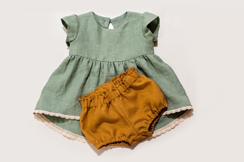 May include: A sage green linen dress with a lace trim and a matching pair of mustard yellow linen bloomers.