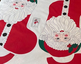 May include: A white fabric panel with a pattern for a Santa Claus stocking. The pattern includes the stocking, Santa's face, beard, and hat, and holly leaves. The text "Stocking and Wall Hanging" is printed at the top of the panel.