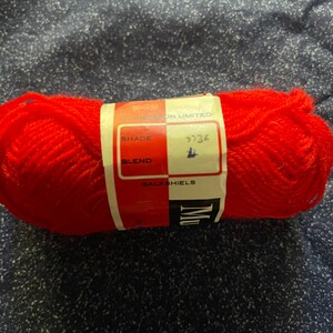 May include: A red ball of yarn with a white label that says "Sunspun Limited", "Shade 9736", "Blend", and "Galahiels".