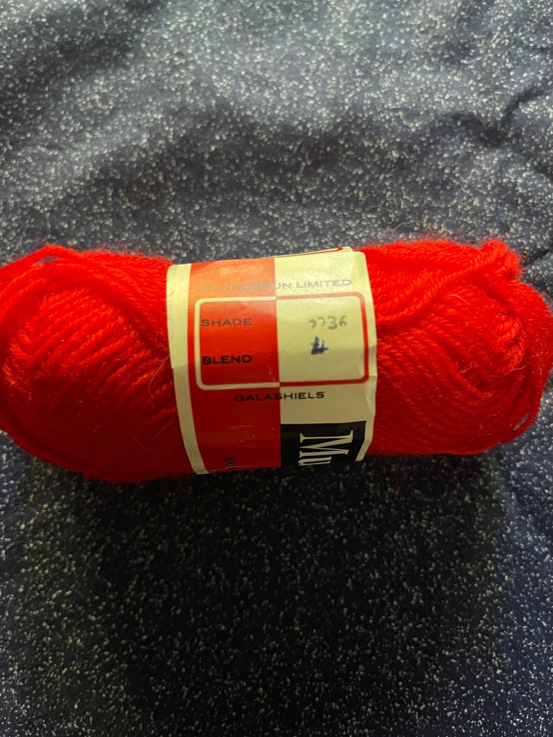 May include: A red ball of yarn with a white label that says "Sunspun Limited", "Shade 9736", "Blend", and "Galahiels".