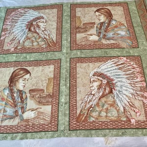 May include: A green and brown fabric with four squares featuring images of Native American people wearing headdresses. Each square has a brown border and a tan background.