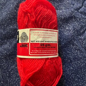 May include: A ball of bright red pure new wool yarn with a white label that reads "PURE NEW wooe" and "NET WEIGHT WHEN PACKED 25 gm. In accordance with BS 984. IN CASE OF COMPLAINTS PLEASE RETURN THIS BAND WITH THE WOOL."