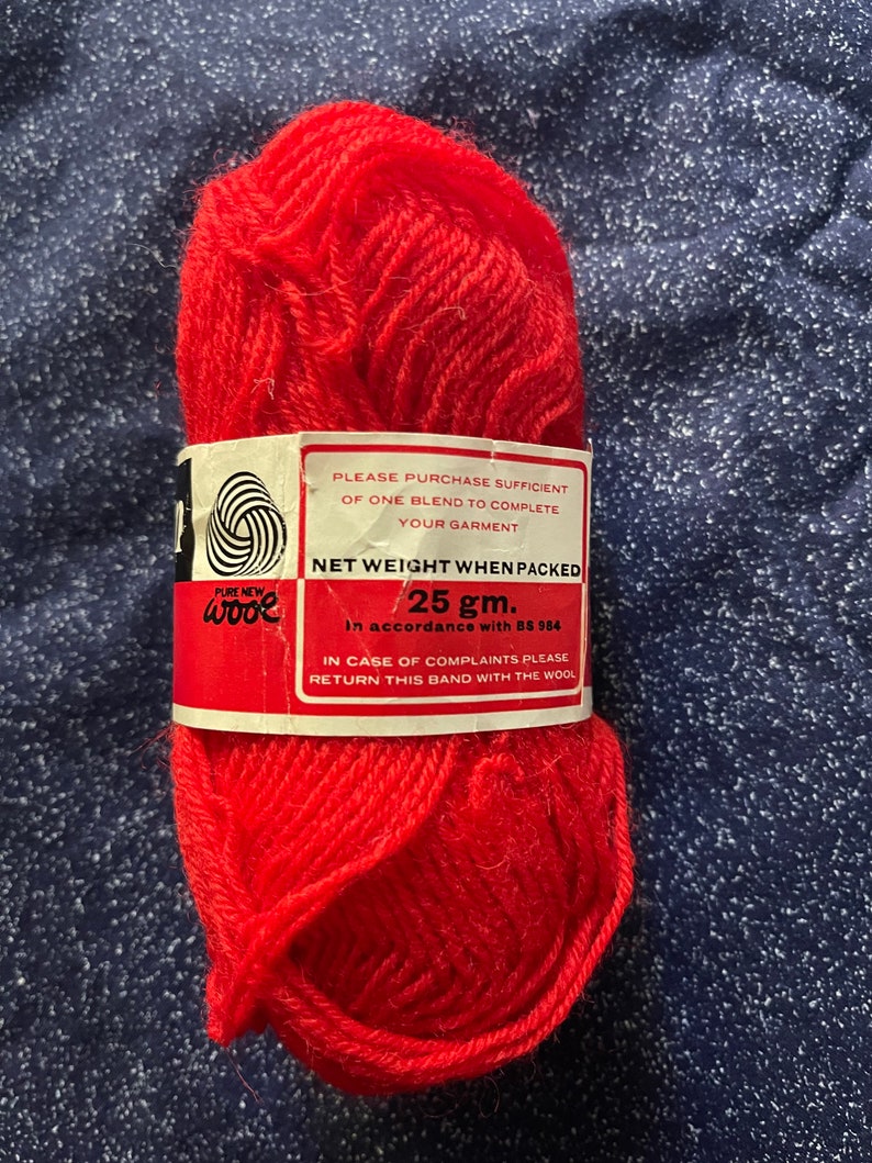 May include: A ball of bright red pure new wool yarn with a white label that reads "PURE NEW wooe" and "NET WEIGHT WHEN PACKED 25 gm. In accordance with BS 984. IN CASE OF COMPLAINTS PLEASE RETURN THIS BAND WITH THE WOOL."