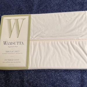 May include: A white Twin flat sheet in its original packaging. The packaging features the brand name "Wamsutta" and product details. The sheet is made of 50% cotton and 50% polyester with a 200 thread count.
