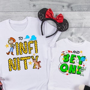 May include: Two white t-shirts with Toy Story characters and text. The larger shirt says "To Infinity and Beyond" with a rope design. The smaller shirt says "And Beyond One" with a rocket and Buzz Lightyear.