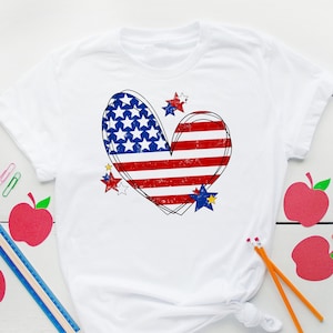 May include: White t-shirt with a red, white, and blue heart-shaped American flag design. The flag is distressed and has stars around it.