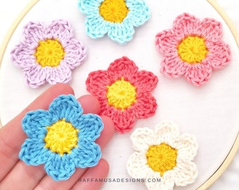 May include: Five crocheted flower appliques in various colors, including pink, blue, white, and purple. Each flower has a yellow center.