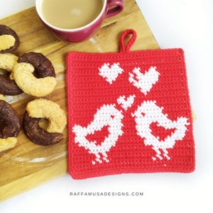 May include: Red crocheted pot holder with a white design of two birds holding hearts. The pot holder has a loop for hanging.