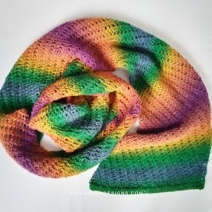 May include: A rainbow colored crochet scarf with a textured stitch pattern. The scarf is folded in half and the ends are overlapping.