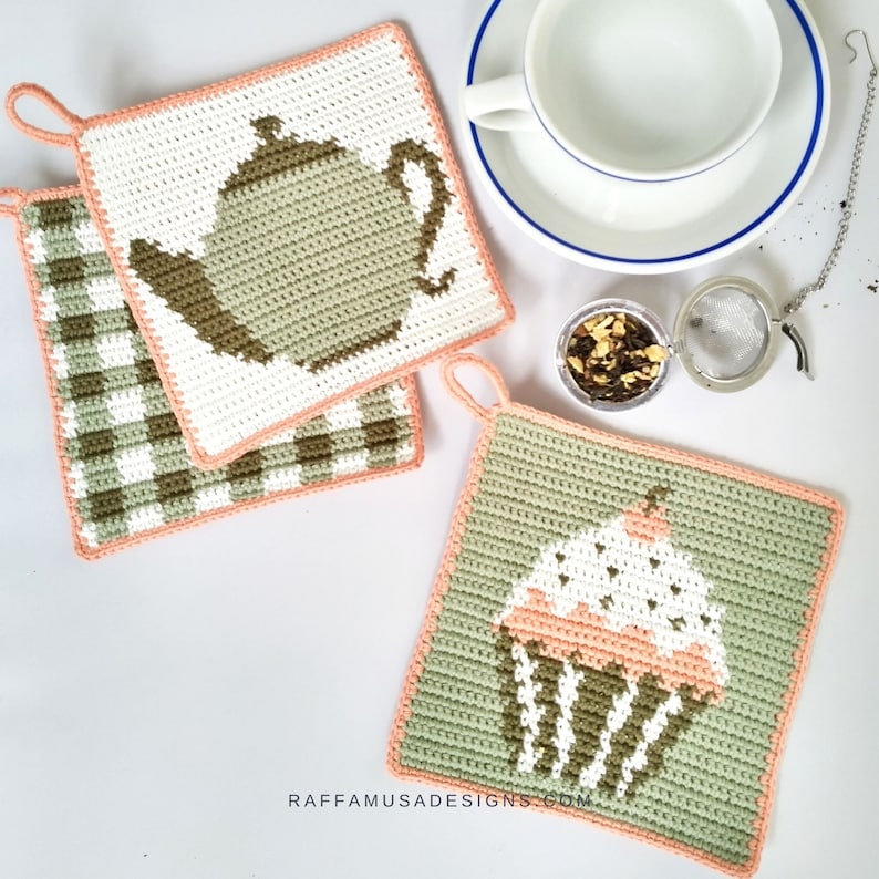 May include: Three crocheted pot holders with a peach border. One pot holder features a green teapot, another features a green and white checkered pattern, and the third features a green cupcake with white frosting and a pink cherry.