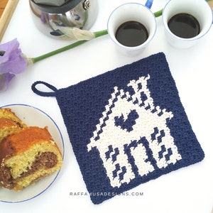 May include: A blue and white crocheted pot holder with a house design. The pot holder has a loop for hanging. The text "RAFFAMUSADESIGNS.COM" is printed on the bottom.
