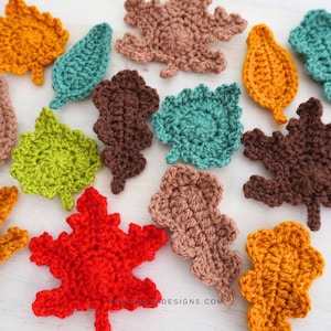 May include: A collection of crocheted leaves in various colours, including orange, green, brown, red, and blue. The leaves are all different shapes and sizes, and they are arranged in a random pattern.