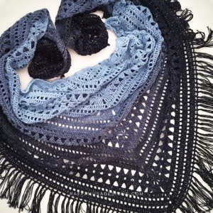May include: A blue and black crochet shawl with a fringe border. The shawl is made with a delicate stitch pattern and has a gradient of color from light blue to black.