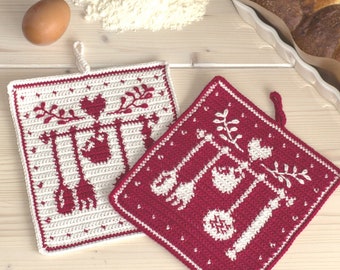 May include: Two crocheted pot holders with a white background and red designs. The designs feature a heart, leaves, and kitchen utensils. The pot holders have a loop for hanging.