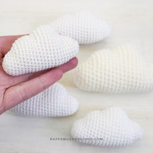 Könnte beinhalten: Fünf weiße gehäkelte Wolken, jede mit einer leicht anderen Form. Die Wolken sind aus weichem, flauschigem Garn gefertigt und perfekt, um jedem Raum einen Hauch von Verspieltheit zu verleihen.