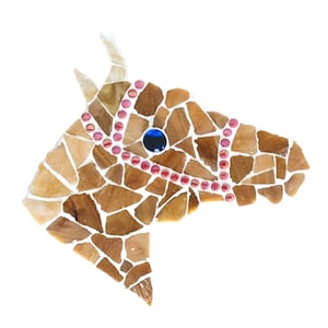 Puede incluir: Escultura de cabeza de caballo de mosaico en tonos marrones y tostados. El caballo lleva una brida rosa y blanca con un ojo azul.