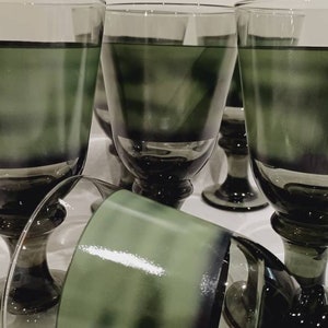 May include: Set of six green glass goblets with a dark green band around the bottom of each glass.