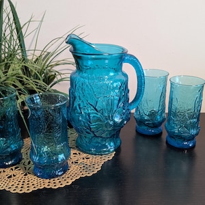 May include: A set of turquoise blue glass pitcher and tumblers with a textured, floral design.